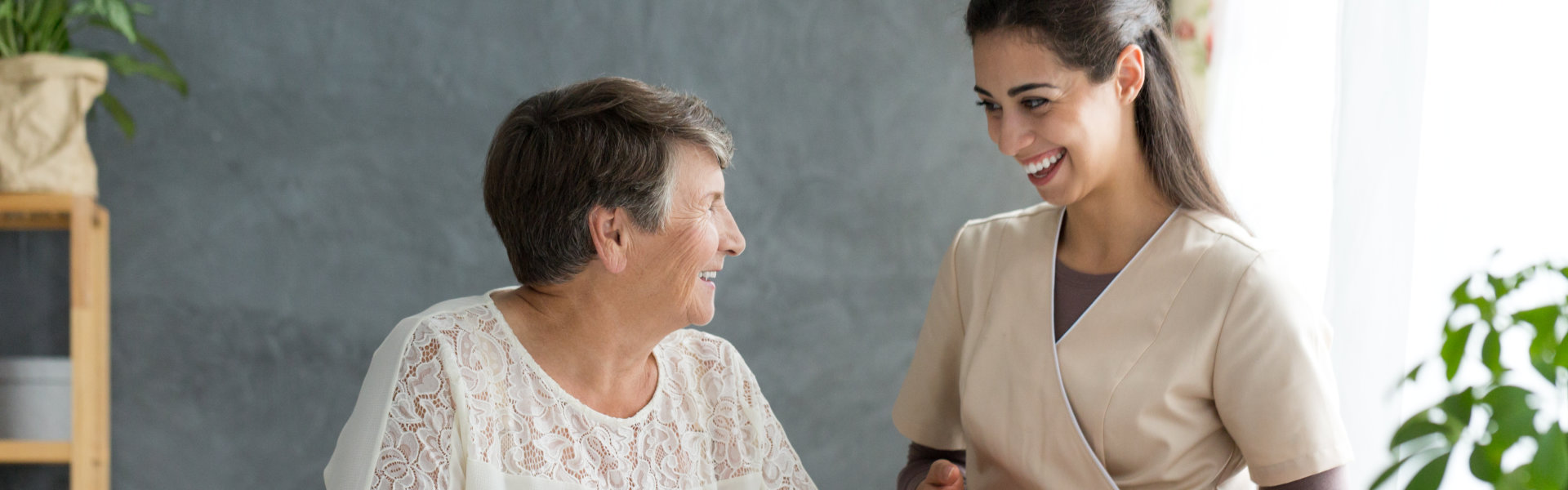 A senior woman and a female caregiver looking at each other