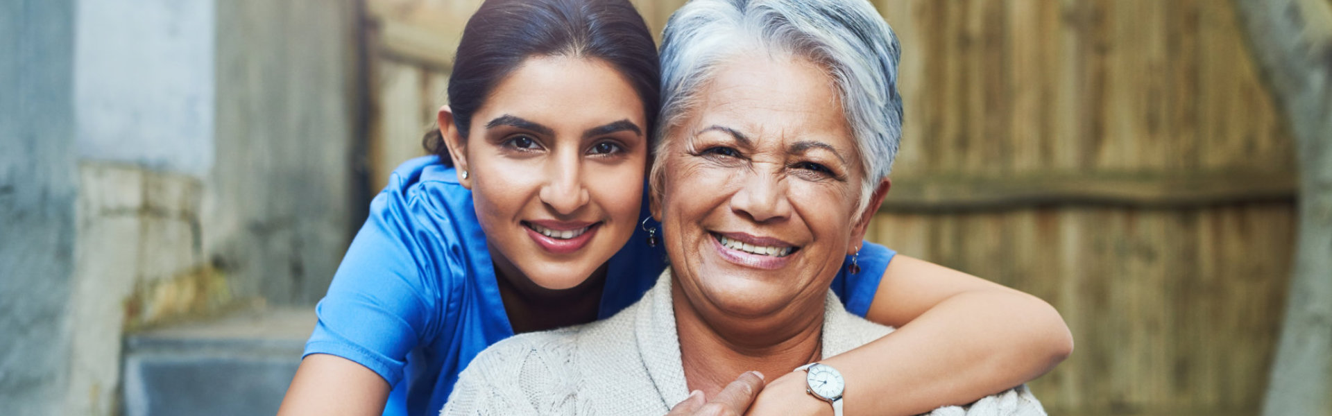 A female caregiver hugging a senior woman sitting