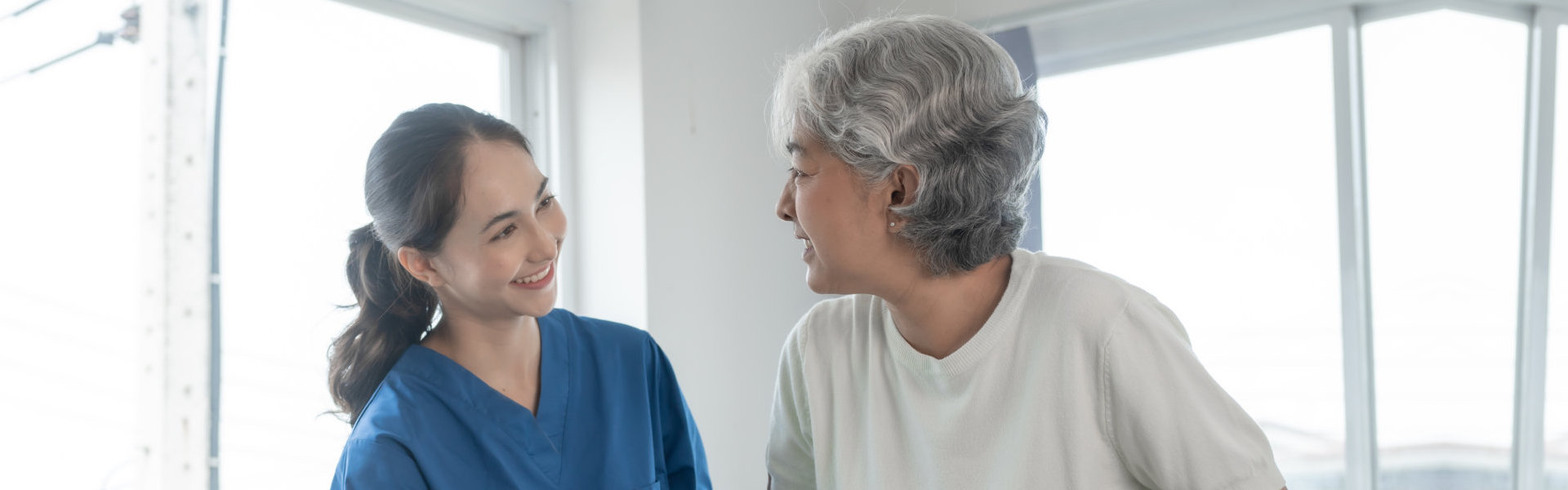 A female caregiver assisting a senior woman to stand